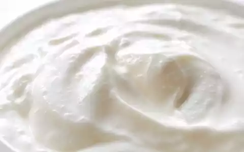 Extreme Makroaufnahme einer cremigen Joghurtoberfläche symbolisiert das Kernprodukt von Danone S.A. FR0000120644 - Foto: THN