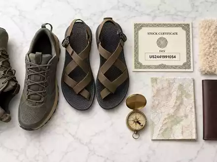 Deckers Outdoor Corp. Schuh-Flatlay auf Marmor mit Aktienzertifikat ISIN-Karte US2441991054 und Kompass - Foto: THN