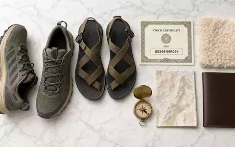 Deckers Outdoor Corp. Schuh-Flatlay auf Marmor mit Aktienzertifikat ISIN-Karte US2441991054 und Kompass - Foto: THN