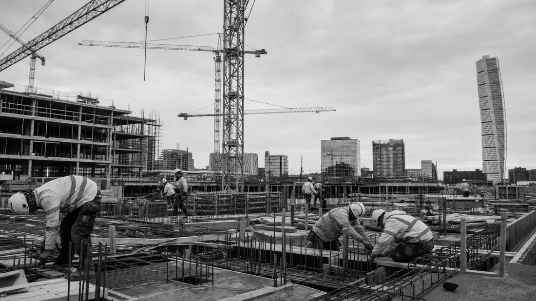 Schwarzweiß-Reportagefoto einer Baustelle mit Kränen vor der Skyline von Malmö