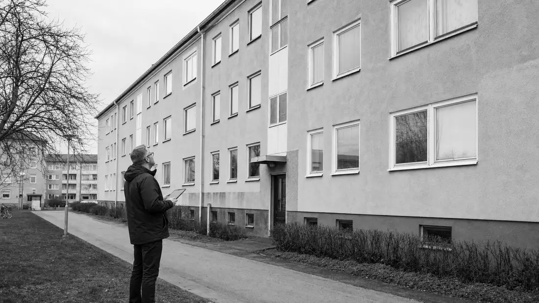 Schwarzweiß-Reportagefoto eines Hausverwalters vor einem schwedischen Wohngebäude