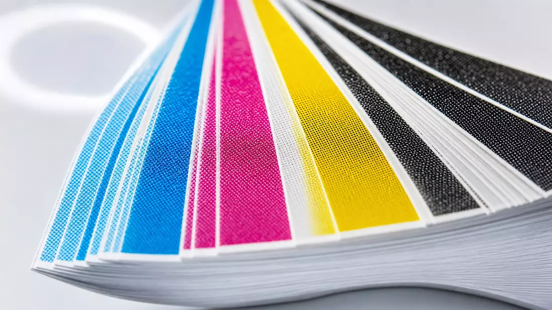 Extreme Makroaufnahme eines aufgefächerten CMYK-Farbmusterfächers mit Bokeh-Hintergrund