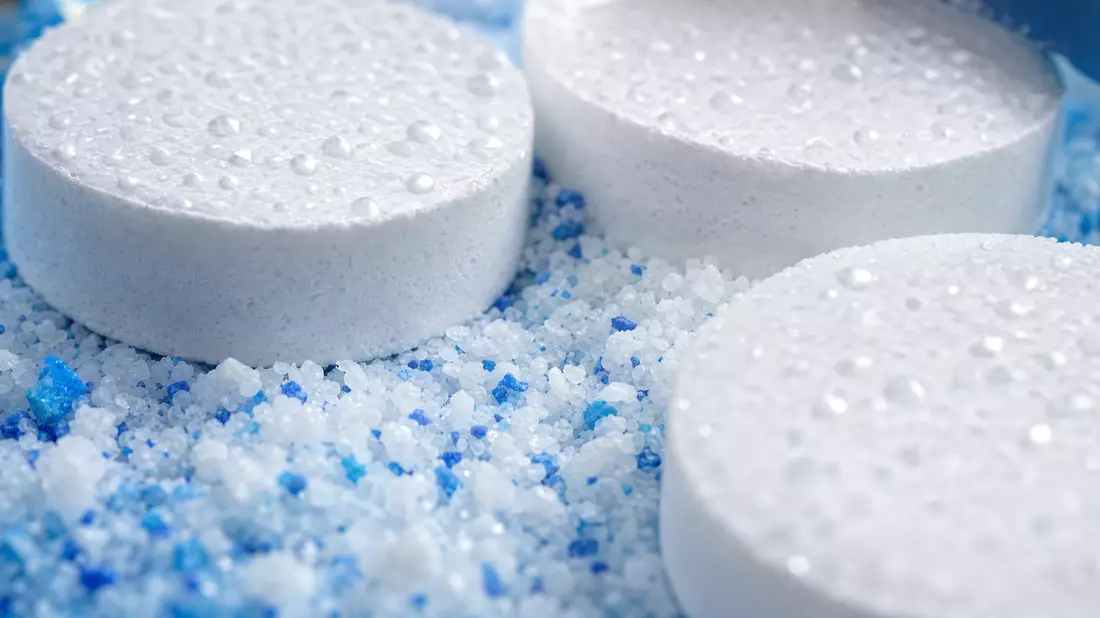 Makroaufnahme von Chlortabletten und Poolchemikalien-Granulat mit Wassertropfen