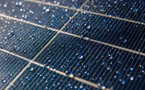 Pinnacle West Capital US7234841010 zeigt eine Makroaufnahme einer Photovoltaikzelle mit Wassertropfen und feinem Metallgitter - Foto: THN
