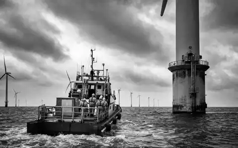 PNE AG (DE000A0JBPG2) dokumentiert Offshore-Windpark in Schwarzweiß mit Serviceschiff und Technikern bei Wartungsarbeiten - Foto: THN