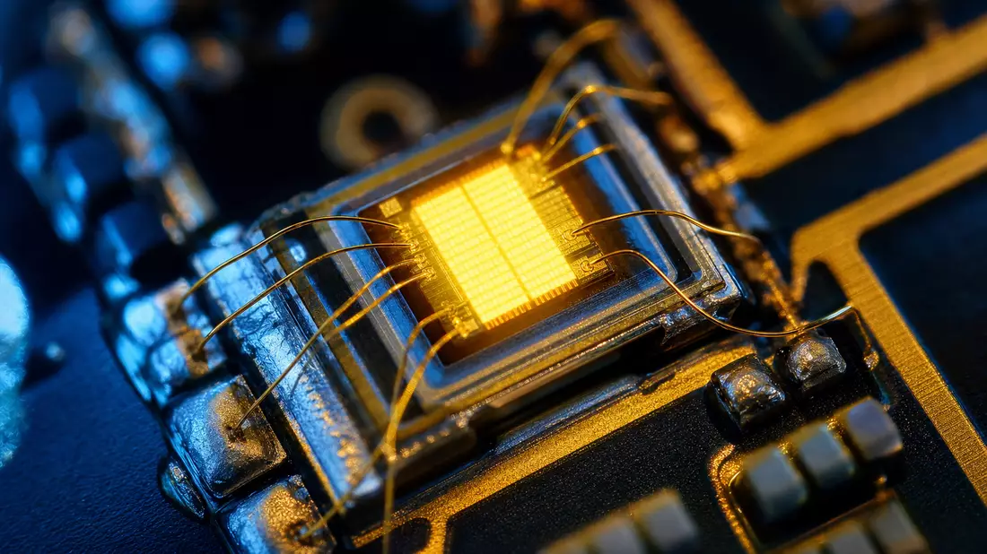 Makroaufnahme eines leuchtenden LED-Chips mit goldenen Drahtverbindungen auf Platine