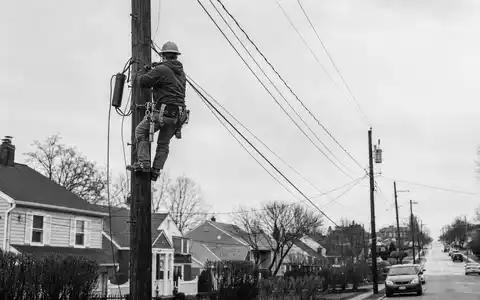 Comcast Corp. Kabeltechniker auf Strommast, dokumentarische Schwarzweiss Reportage zur ISIN US20030N1019 Telekommunikation - Foto: THN