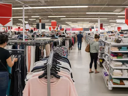 TJX Companies Inc. (US8725401090) betreibt Off-Price-Läden, hier eine belebte Verkaufsfläche mit Kleiderständern - Foto: THN