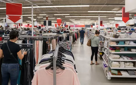 TJX Companies Inc. (US8725401090) betreibt Off-Price-Läden, hier eine belebte Verkaufsfläche mit Kleiderständern - Foto: THN