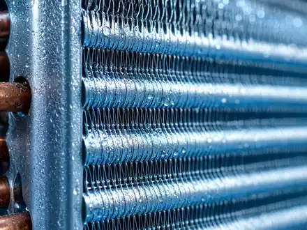 Trane Technologies (IE00BK9ZQ967): Makroaufnahme zeigt einen Kühlrippen-Wärmetauscher mit glänzenden Kupferrohren und feinen Kondenswassertropfen - Foto: THN