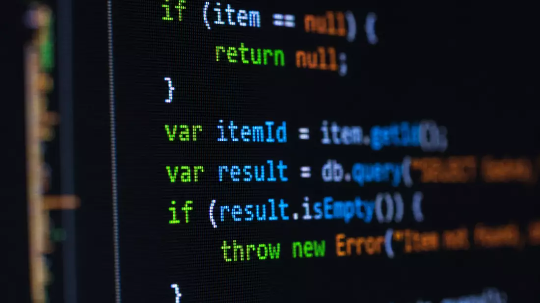 Makro-Aufnahme: Farbiger Syntax-Code auf dunklem Bildschirm in Nahaufnahme