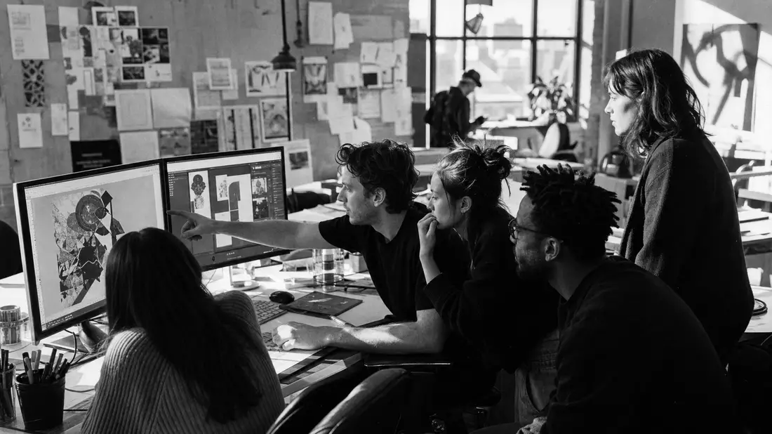 Kreativteam im Studio vor Monitoren, Schwarz-Weiß – Adobe Inc. US00724F1012