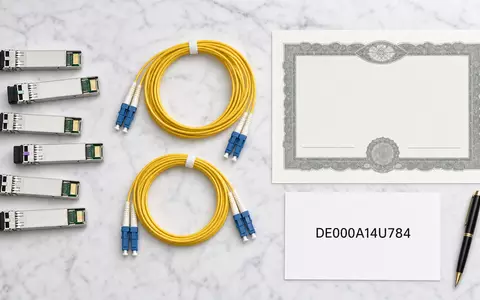 Adtran Networks SE DE000A14U784 – Flatlay mit generischen SFP-Modulen, Glasfaserkabeln, Aktienzertifikat und ISIN-Karte auf Marmor - Foto: THN