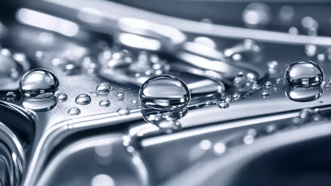 Extreme Makroaufnahme glitzernder Wassertropfen auf poliertem Chrommetall