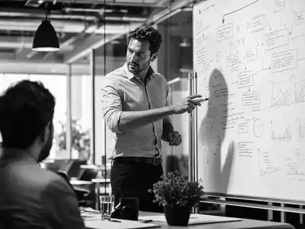 Accenture plc IE00B4BNMY34 schwarz weißes Reportage Foto eines Beraters am Whiteboard mit Strategie - Foto: THN