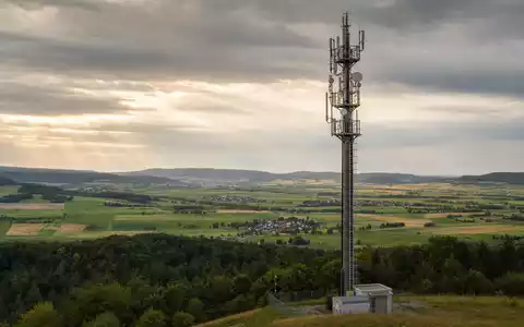 Fotorealistischer 5G-Mobilfunkmast von 1&1 AG in hügeliger Landschaft steht für ISIN DE0005545503 - Foto: THN