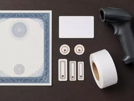 Zebra Technologies (US9892071054) Flatlay mit Aktienzertifikat, ISIN-Karte, Barcode-Scanner und kleinen RFID-Etiketten arrangiert - Foto: THN