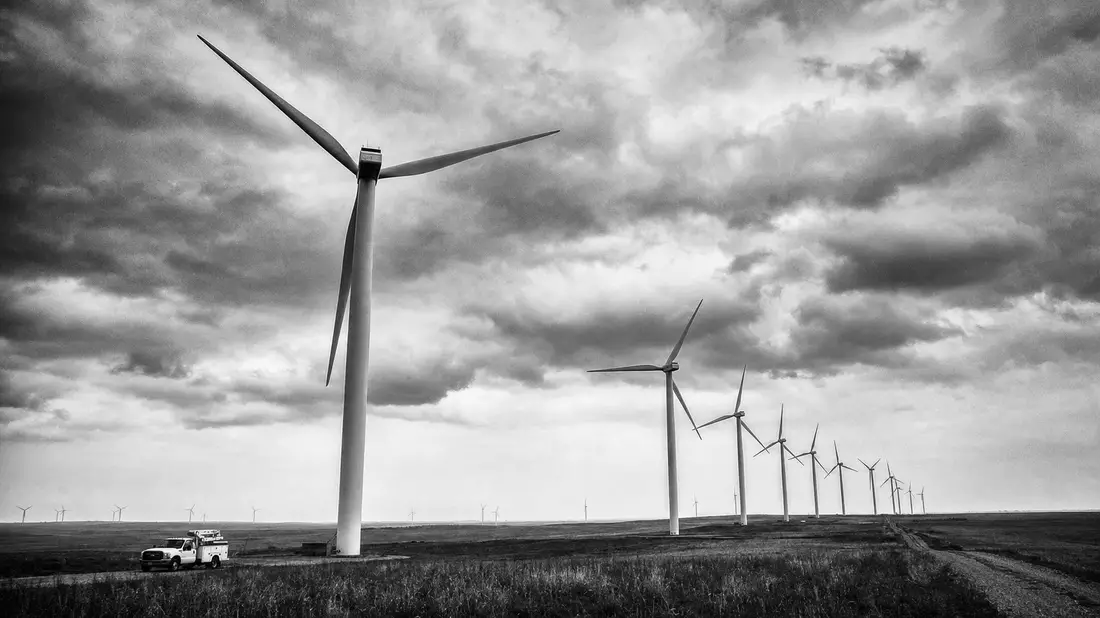 Schwarzweiß-Reportagefoto eines Windparks mit Servicewagen auf weiter Prärie