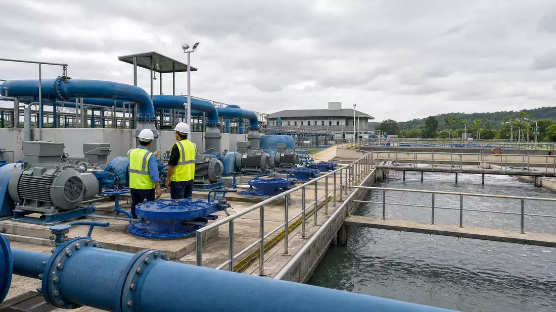 Industrielle Wasseraufbereitungsanlage mit blauen Pumpen und Becken bei bewölktem Himmel