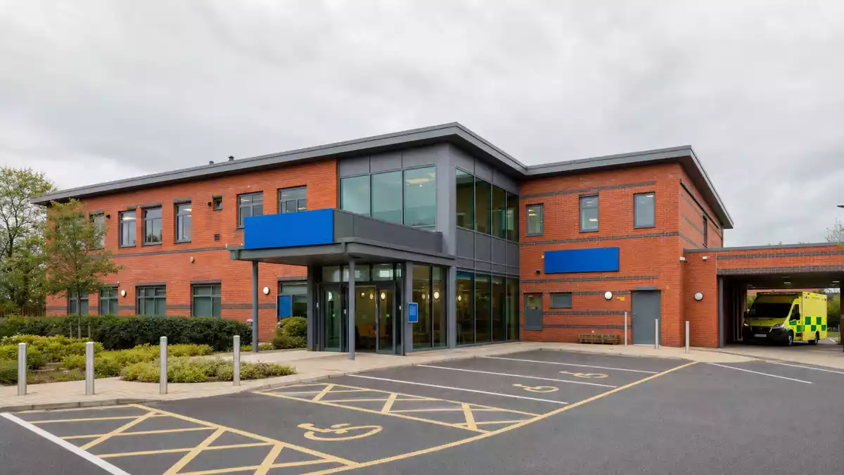 Modernes Hausarztpraxis-Gebäude mit roter Backsteinfassade und Krankenwagen-Zufahrt in Großbritannien