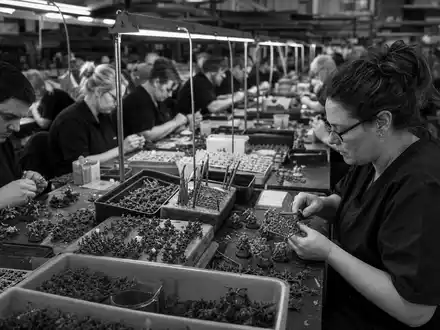 Games Workshop Group PLC (ISIN GB0003718474) Produktionsmitarbeiter montieren Kunststoff-Modellbausätze in dokumentarischer Schwarzweiß-Aufnahme - Foto: THN