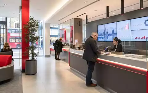 Fotorealistische Bankfiliale symbolisiert Virgin Money UK PLC (ISIN GB00BD6GN030) im britischen Retail-Bankensektor mit modernem Design - Foto: THN