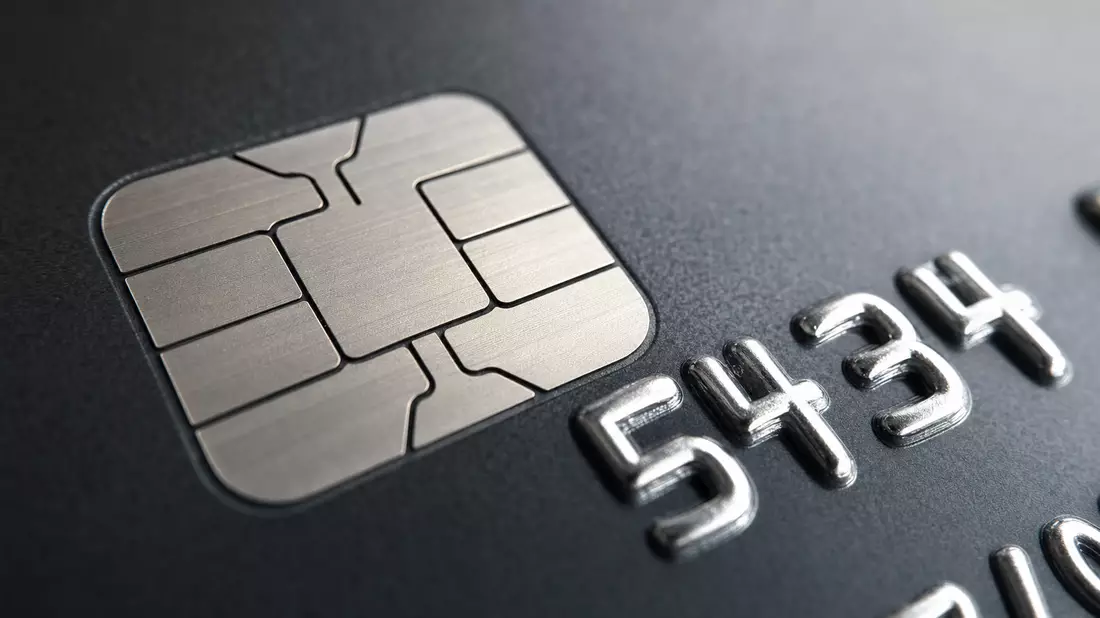 Extreme Nahaufnahme eines Chips und geprägter Ziffern auf einer dunklen Bankkarte