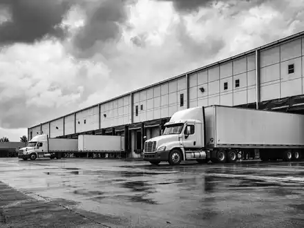 Schwarzweiß-Reportagefoto zeigt LKW an Verladerampen, passend zum Geschäft von WDP N.V., Wertpapier BE0974310428 - Foto: THN