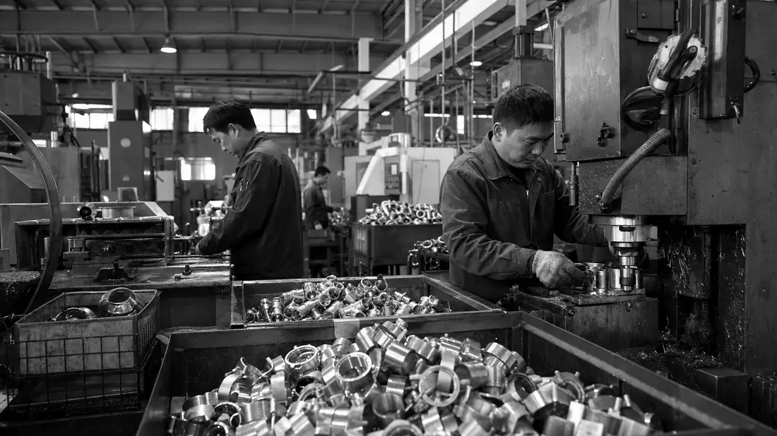 Schwarz-Weiß-Reportagefoto von Arbeitern in einer Metallteile-Fabrik