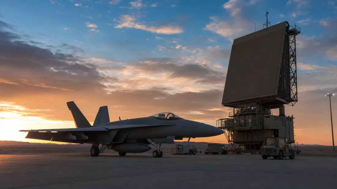 Militärjet und Radarturm auf Wüstenflugplatz bei Sonnenuntergang
