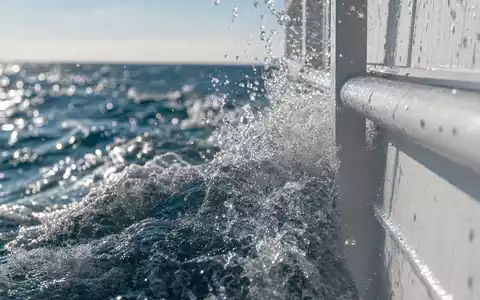 Norwegian Cruise Line BMG667211046 zeigt eine Makroaufnahme von spritzendem Wasser an einer generischen Schiffsreling - Foto: THN