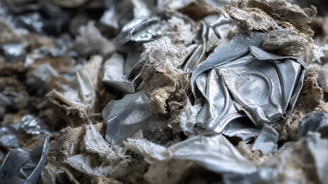 Makroaufnahme von zerkleinertem Papier und zerdrückten Aluminiumdosen in Nahaufnahme