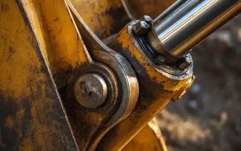 Wacker Neuson SE (DE000WACK012) zeigt eine Makroaufnahme eines verwitterten Hydraulikgelenks am gelben Baggerarm mit Kratzern - Foto: THN