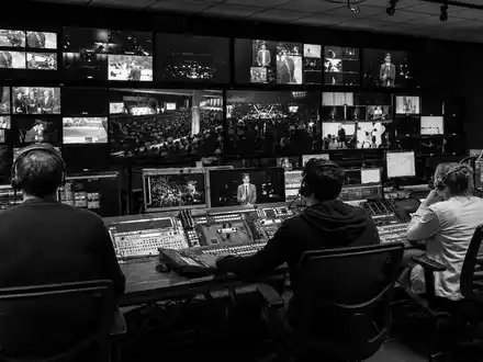 Fox Corp. (Class B) Aktie US35137L2043 zeigt dokumentarische Schwarzweiß-Aufnahme im Broadcast-Kontrollraum mit Monitoren - Foto: THN