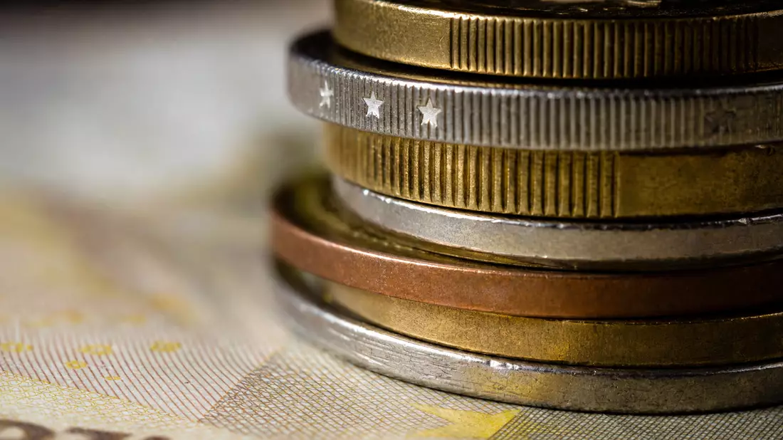 Makroaufnahme gestapelter Euro-Münzen mit feinen Details auf Banknotenpapier