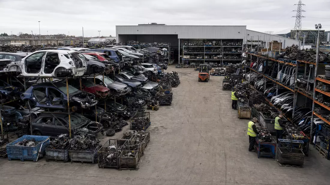Fotorealistische Ansicht einer Autoteile-Recyclinganlage mit Werkshallen und sortierten Ersatzteilen