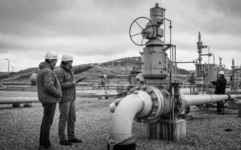 Loews Corporation US5404241031 dokumentiert schwarzweiß zwei Techniker bei der Inspektion einer industriellen Pipeline-Ventilstation im Freien - Foto: THN