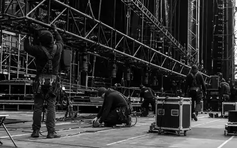 Live Nation Entertainment (ISIN US5380341090) beschäftigt Bühnencrews, dokumentarisch in Schwarzweiß beim Aufbau festgehalten - Foto: THN