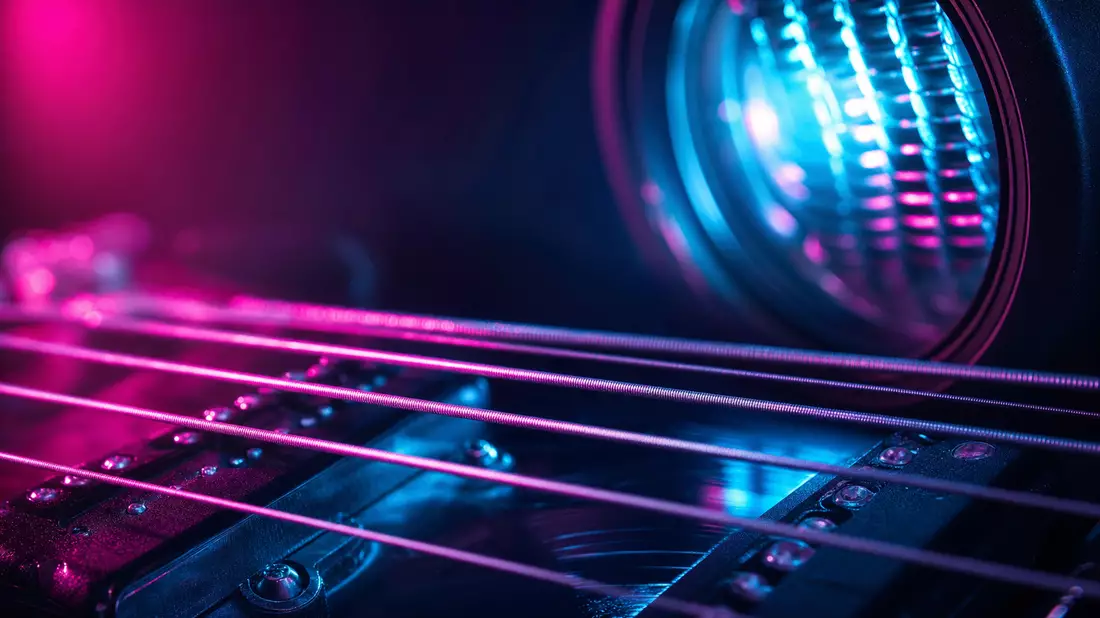Makroaufnahme von Gitarrensaiten mit farbigem Bühnenlicht-Bokeh