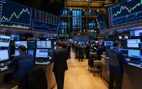 Crown Castle Inc. NYSE-Handelsparkett US22822V1017 zeigt Händler vor Monitoren mit Telekommunikationssektor-Charts bei Hochbetrieb - Foto: THN