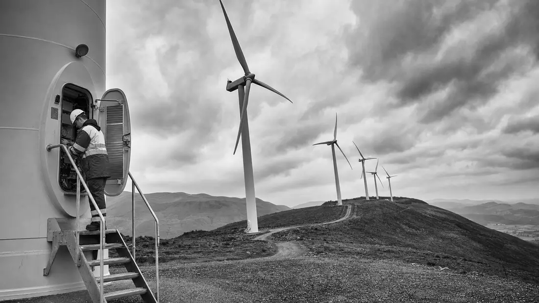 Dokumentarische Schwarzweiß-Aufnahme eines Windparks mit Ingenieuren