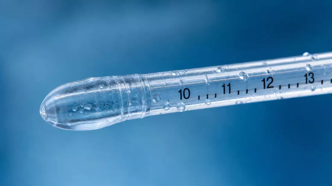Makroaufnahme einer durchsichtigen Katheterspitze aus medizinischem Silikon mit Wassertropfen