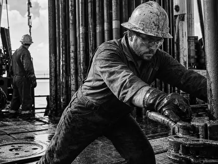 Occidental Petroleum US6745991058 dargestellt als Schwarz-WeiĂź-Reportage eines Bohrinsel-Technikers bei intensiver, konzentrierter Arbeit vor Ort - Foto: THN