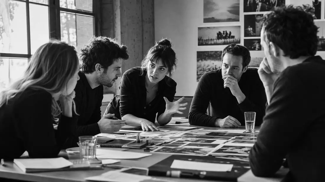 Schwarz-weißes Reportagefoto eines Brainstormings am Tisch mit Fotolayouts