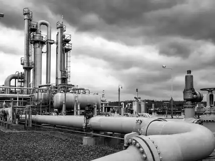 ONEOK Inc. (ISIN US6826801036) Schwarz-WeiĂ-Reportagefoto einer industriellen Erdgas-Kompressorstation mit dramatischem bewölktem Himmel im Hintergrund - Foto: THN
