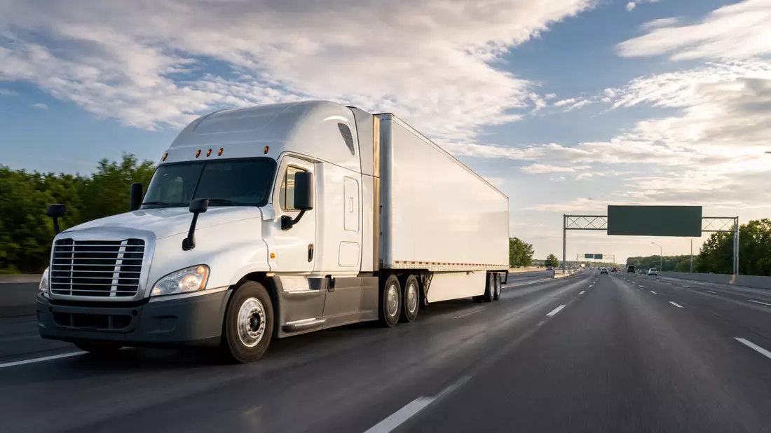 Weißer generischer Sattelzug fährt auf mehrspuriger US-Autobahn bei Sonnenschein