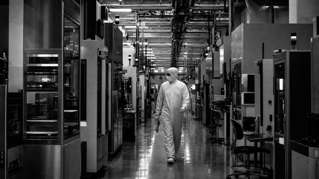 Schwarz-weiße Reportagefotografie eines Ingenieurs im Schutzanzug in einer Chipfabrik