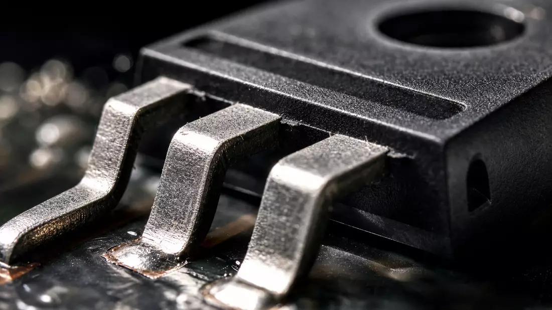 Extreme Nahaufnahme eines Leistungshalbleitergehäuses mit glänzenden Metallanschlüssen