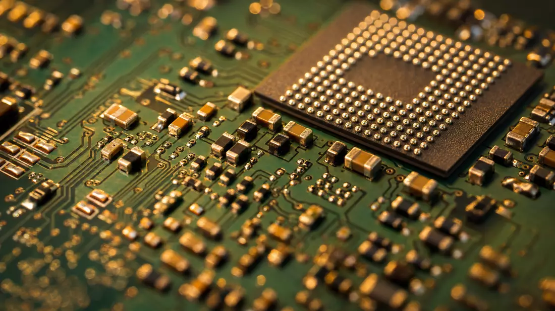Extreme Makroaufnahme einer grünen Leiterplatte mit goldenen SMD-Widerständen und BGA-Chip