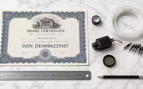 Jenoptik AG DE0006229107 Flatlay mit Aktien Zertifikat ISIN Karte optischer Linse und Laser Modul - Foto: THN